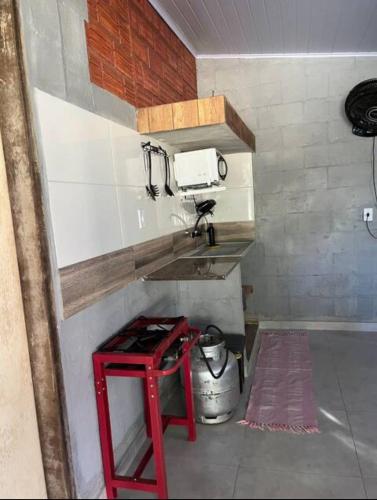 a kitchen with a red stool next to a sink at Hostel Sossego do Garças in Barra do Garças