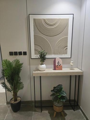 a table with two plants and a picture on the wall at روح المدينة السكنية in Al Madinah