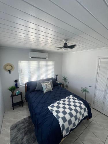 a bedroom with a bed with a blue comforter and a ceiling at All Decked Out, Exuma in Georgetown