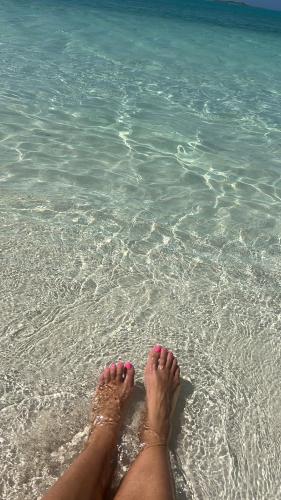 a person laying on the beach with their feet in the water at All Decked Out, Exuma in Georgetown