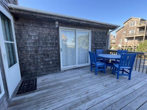 a patio with blue chairs and a table on a deck at CHASING SUNSETS cottage in Hatteras