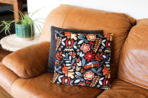 a pillow on a couch with a flower pattern at Apostle Hideaway - Central Port Campbell in Port Campbell