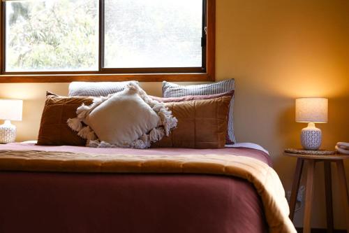 a bedroom with a bed with pillows and a window at Red ceder cottage - Great ocean road - Port Campbell in Port Campbell