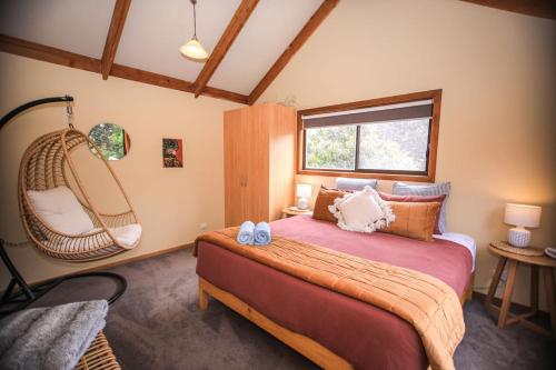 a bedroom with a large bed and a hanging chair at Red ceder cottage - Great ocean road - Port Campbell in Port Campbell