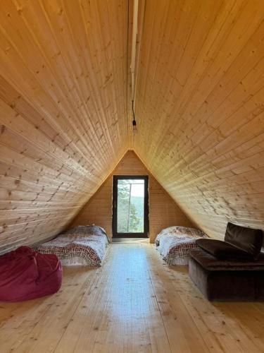a large wooden room with two beds and a window at Bakhmaro Lodge in Chʼkhakoura