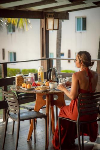 a woman in a red dress sitting at a table at Pecem Beach Hotel - Aval Hotel in Pecém