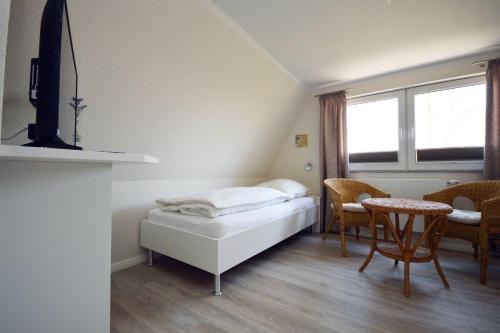 ein kleines Zimmer mit einem Bett, einem Tisch und einem Fenster in der Unterkunft Aalreuse in Südbrookmerland