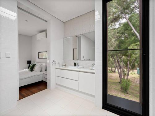 a white bathroom with a sink and a mirror at Sophie's Vineyard - Sprawling Scenery with Pool in Yallingup Siding