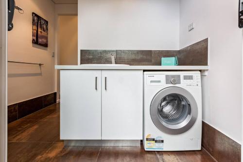 a white laundry room with a sink and a washing machine at Sunrise Tranquillity - Luxe Retreat with Heated Spa in Yallingup Siding