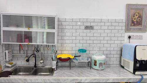 een keuken met een wastafel en een tafel in een keuken bij Mariamz Homestay near jetty Perhentian Island in Kampong Baru