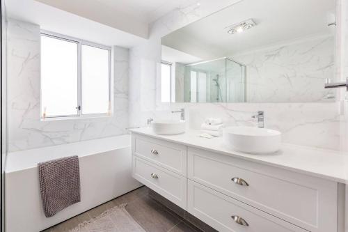 a white bathroom with two sinks and a tub and a mirror at Reverie By The Bay - Walk to Beaches, Relax in Style in Dunsborough