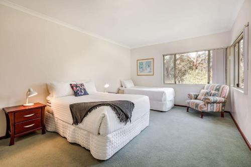 une chambre blanche avec un lit et une chaise dans l'établissement The Nest - Tranquil Bush Retreat near Dunsborough, à Yallingup Siding