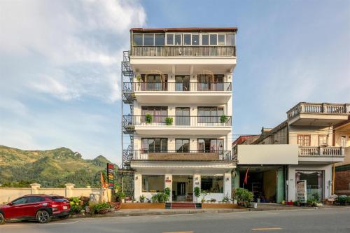 a tall white building with a red car parked in front at Glow Sapa Hotel in Sa Pa