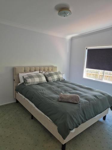 a bedroom with a bed with a green blanket and a window at Carthage Terrace in Tamworth