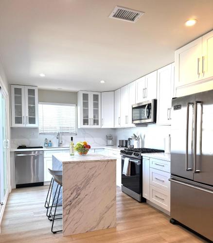 a kitchen with white cabinets and stainless steel appliances at Coastal Escape in Redondo Beach in Redondo Beach