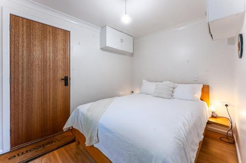 a bedroom with a white bed and a wooden door at Central Castlemaine studio on steam train line in Castlemaine