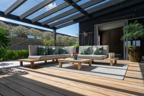 eine Terrasse mit Sofas und Tischen auf einer Terrasse in der Unterkunft Lake View Lodge in Taupo Airport