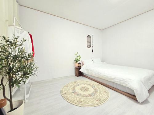 a white bedroom with a bed and a rug at Bitdamjip Near Hwaseong Fortress and Suwon Station in Suwon