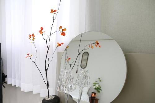 a mirror on a table with a vase with flowers at Bitdamjip Near Hwaseong Fortress and Suwon Station in Suwon