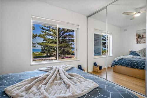 a bedroom with a bed and a large window at Beachfront self contained upstairs apartment in Semaphore
