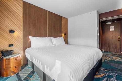 a bedroom with a large bed and a wooden wall at George Hotel Launceston, an Ascend Collection Hotel in Launceston