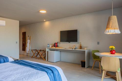 a bedroom with a bed and a table and a tv at Saline Taíba Boutique Beach Hotel in Taíba