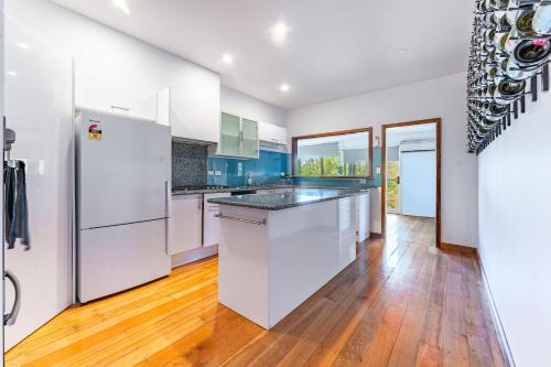 an empty kitchen with white appliances and wood floors at Central View Eco Home in Castlemaine