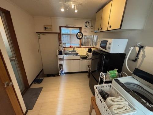 eine kleine Küche mit Spüle und Mikrowelle in der Unterkunft サンハウス六本松103 in Susakiuramachi