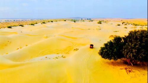 a truck driving through a desert with sand at HAMIRGARH LUXURIOUS DESERT CAMP & RESoRT in Jaisalmer