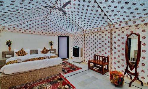 a bedroom with a bed and a mirror at HAMIRGARH LUXURIOUS DESERT CAMP & RESoRT in Jaisalmer