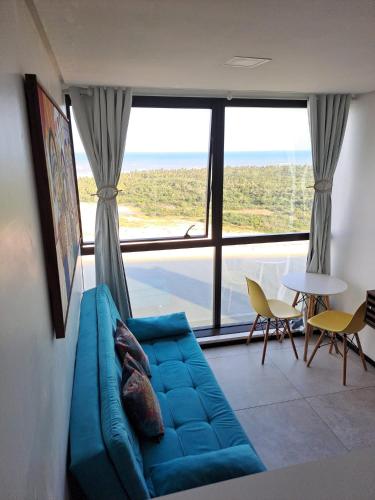 a living room with a blue couch and a large window at FLAT BEIRA MAR BARRA DE JANGADA ANDAR ALTO JABOATão in Recife
