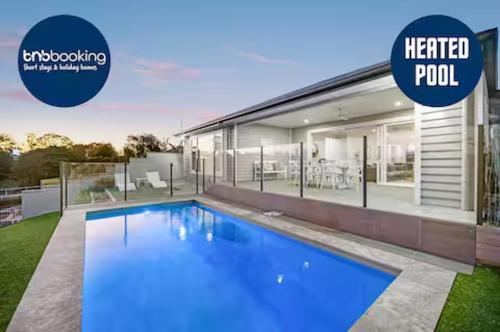 a house with a heated pool in front of it at Capri Waterfront Resort-Style 5BR & Pool in Gold Coast