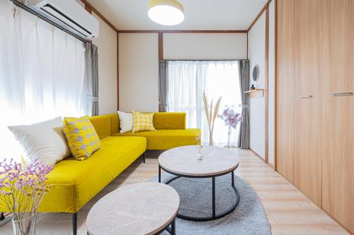 a living room with a yellow couch and a table at Happiness Ohama一軒家東名静岡インター五分 in Shizuoka