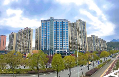 a city with tall buildings and a street with trees at Zhangjiajie Merlot Crystal Hotel in Zhangjiajie