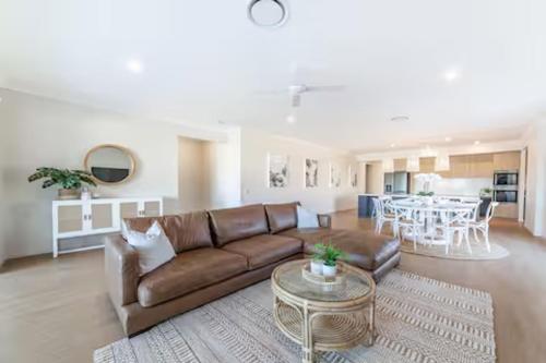 a living room with a brown couch and a table at Capri Waterfront Resort-Style 5BR & Pool in Gold Coast