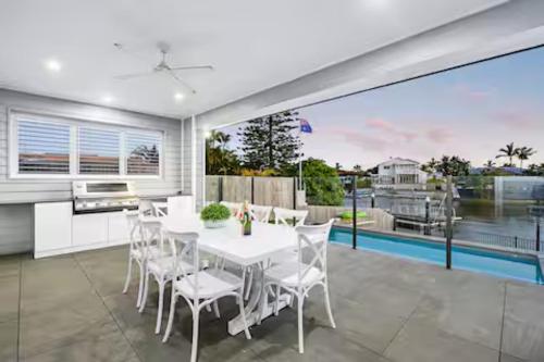 a dining room with a white table and chairs at Capri Waterfront Resort-Style 5BR & Pool in Gold Coast