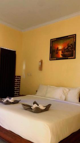 a bedroom with a white bed with a picture on the wall at Eco Moringa Garden in Banyuwedang