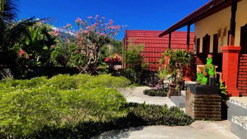 a garden with green plants and a red building at Eco Moringa Garden in Banyuwedang