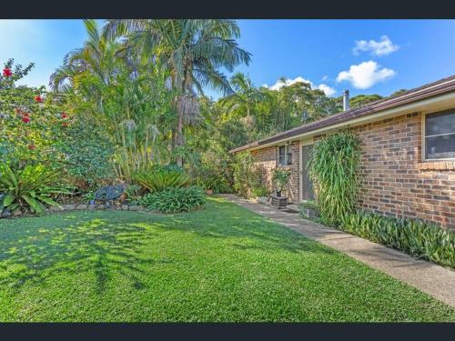 a brick house with a yard with grass and trees at Bush & Beach Haven by One Mile Beach in Forster