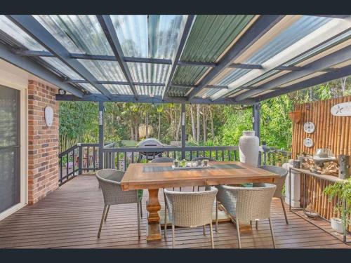 a patio with a wooden table and chairs on a deck at Bush & Beach Haven by One Mile Beach in Forster