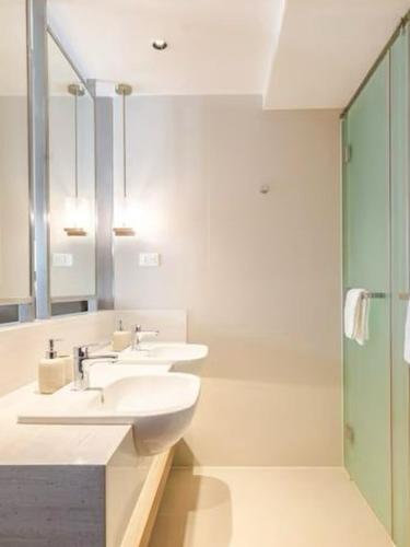 a bathroom with two sinks and a shower at Novotel Rockwell View Hotel Residences in Manila