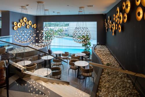 a restaurant with tables and chairs and chandeliers at Novotel Rockwell View Hotel Residences in Manila