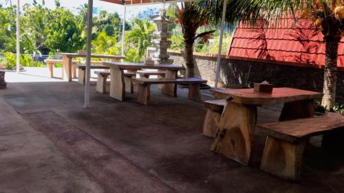 a group of picnic tables sitting next to a building at Eco Moringa Garden in Banyuwedang