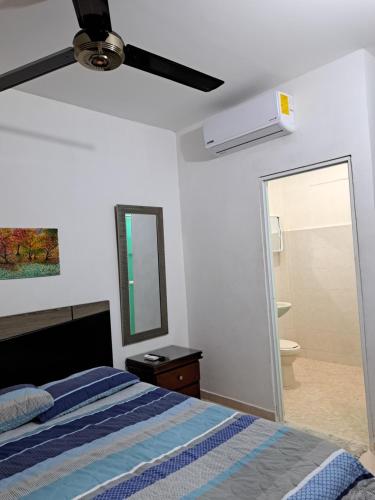 1 dormitorio con 1 cama con ventilador de techo y espejo en Arriendo habitaciones amobladas con aire acondicionado, en Montería