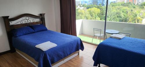 a bedroom with two beds and a view of a balcony at Apartamento Reforma Ciudad de Guatemala in Guatemala