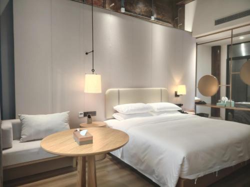 a bedroom with a large bed and a table at Floral Hotel Taipingli in Quanjiao