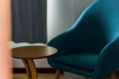 a blue chair sitting next to a wooden table at 犬山口駅10分 80インチ映画館有 無料駐車場 ベッド6台 ソファベッド1台 83平米 最大10名宿泊可 in Inuyama