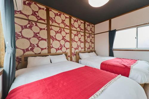 two beds in a room with red and white at 犬山口駅10分 80インチ映画館有 無料駐車場 ベッド6台 ソファベッド1台 83平米 最大10名宿泊可 in Inuyama