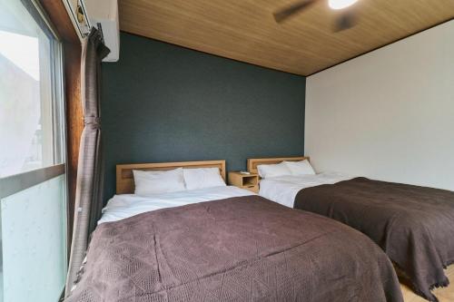 two beds in a room with green walls at 犬山口駅10分 80インチ映画館有 無料駐車場 ベッド6台 ソファベッド1台 83平米 最大10名宿泊可 in Inuyama