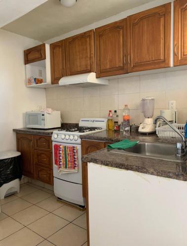 a kitchen with wooden cabinets and a white stove top oven at Agradable y amplio depa cerca del metropolitano in Guadalajara
